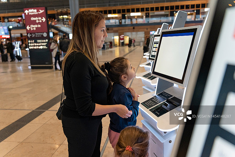 母亲和两个女儿在机场自助值机图片素材