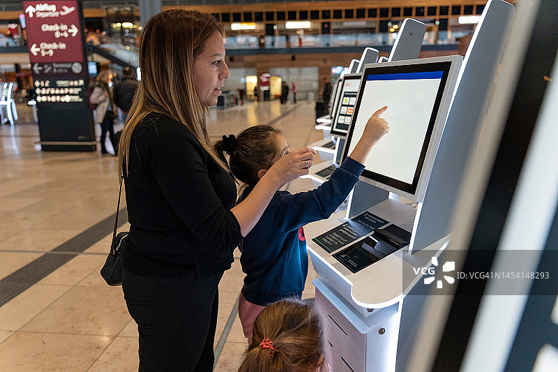 母亲和两个女儿在机场自助值机图片素材