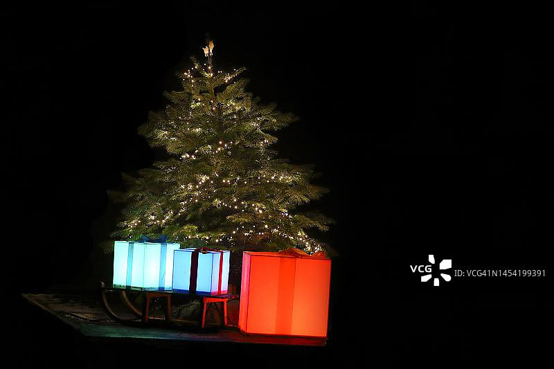 带有雪橇和礼物的发光圣诞树，夜景，锡格尔兰，北莱茵-威斯特法伦州，德国图片素材