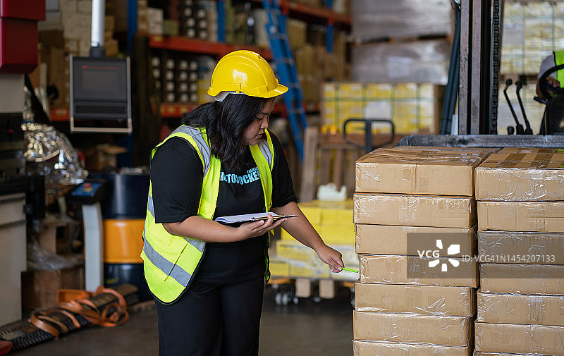 女人在仓库检查货物清单图片素材