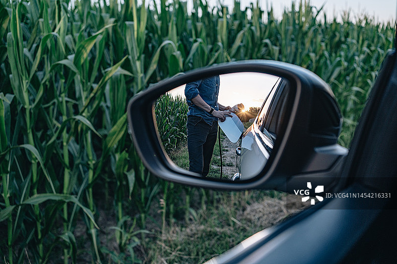 年轻男人为电动汽车充电图片素材