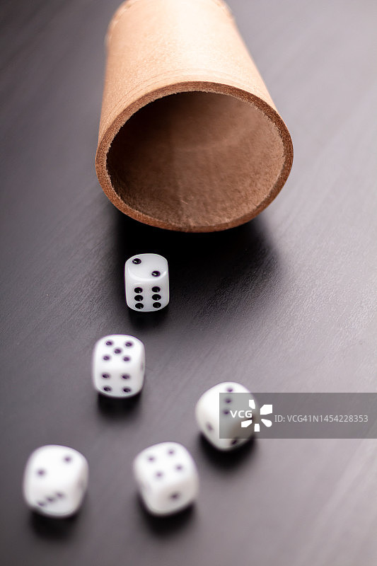 黑色背景上从骰盅中洒出的骰子图片素材