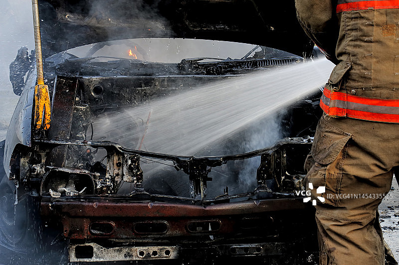 消防员使用消防水带向燃烧的汽车喷水图片素材