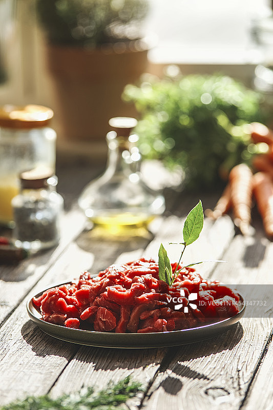 厨房餐桌上盘子里的生肉切片及配料，特写图片素材