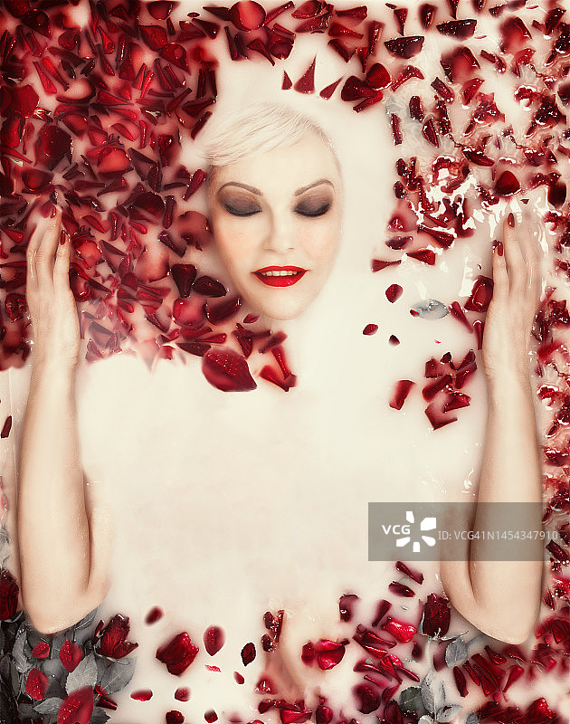在牛奶浴中撒满红色玫瑰花瓣的美女图片素材