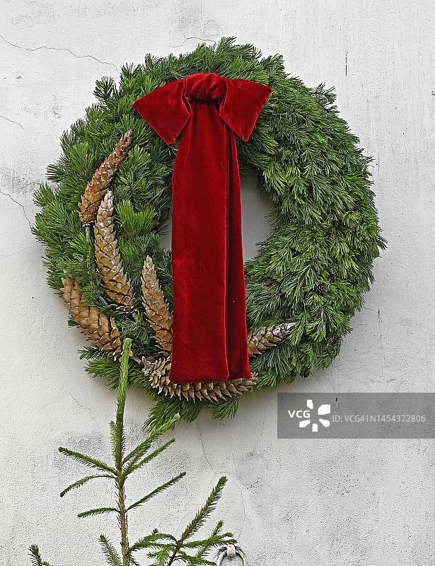 用天鹅绒红丝带和松果装饰的天然松树花环图片素材