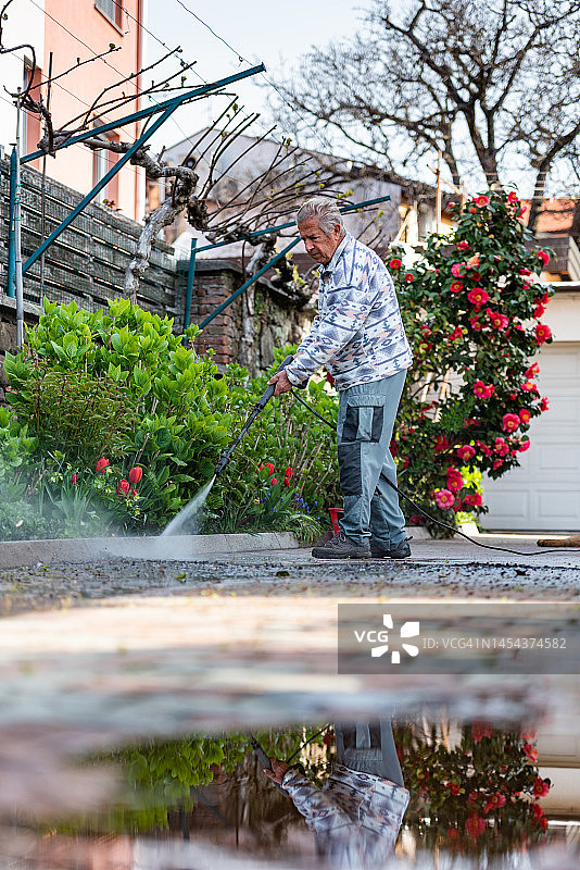 老年男人在家用高压清洗机清理院子图片素材