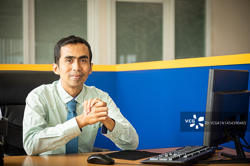坐在办公桌旁的亚洲男人图片素材