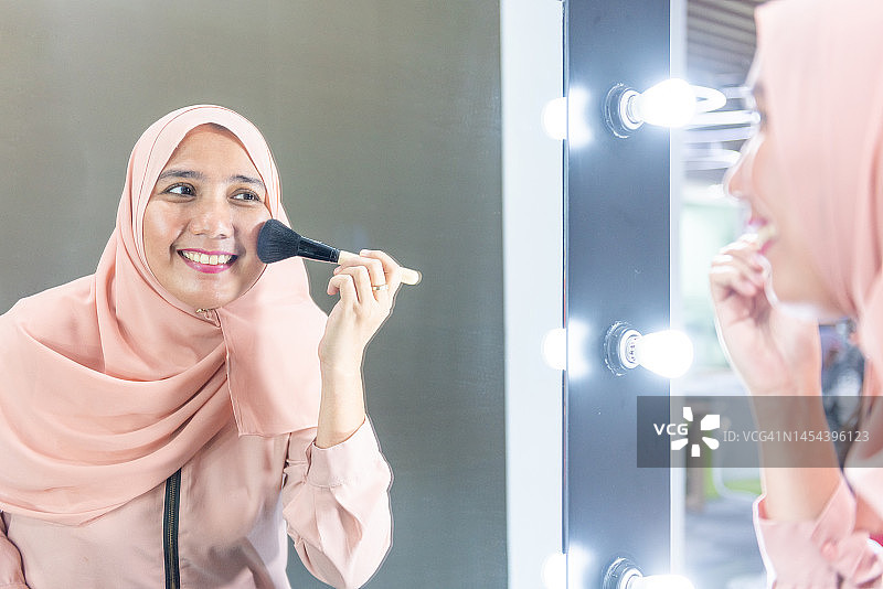 漂亮的穆斯林女子在脸颊上涂腮红图片素材