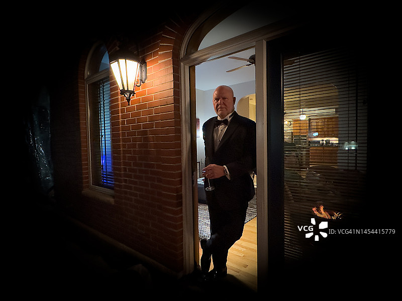 穿着燕尾服的男人在门口放松地喝着饮品图片素材