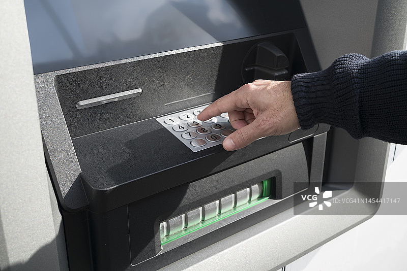男人在早晨街上的自动取款机上输入密码图片素材