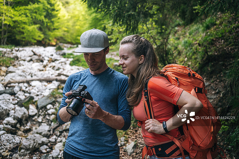 摄影师向背包客展示屏幕上的图像图片素材