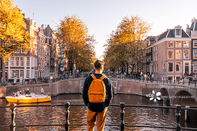 晴天，在荷兰阿姆斯特丹运河边看风景的男人的背影图片素材