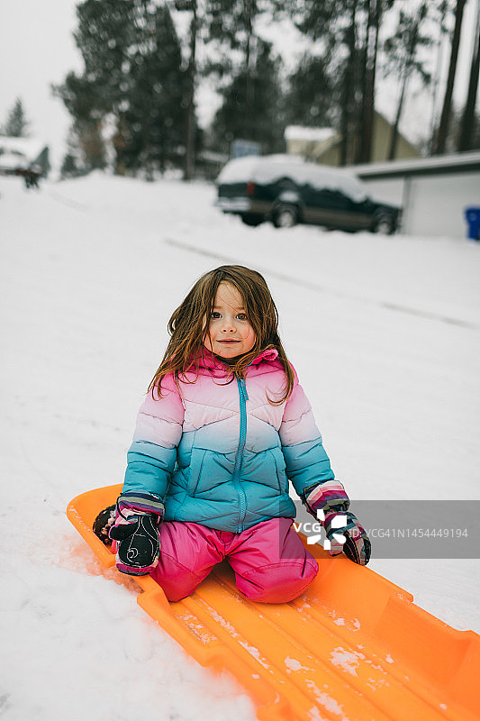 在社区玩雪橇的可爱小女孩图片素材