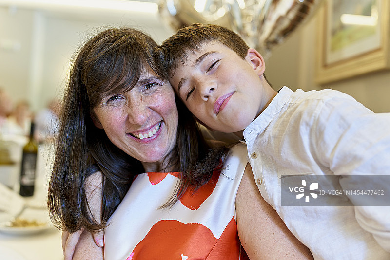 优雅的白人母亲和儿子在餐厅里幸福地看着镜头图片素材