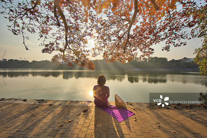 身穿传统奥黛在还剑湖旁摆姿势的老年妇女图片素材
