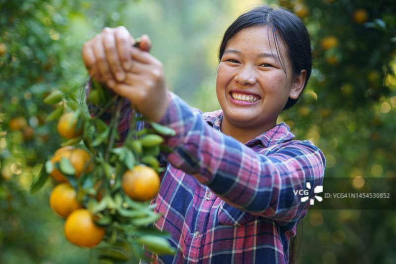 自信微笑手捧橙子的青年女农民图片素材