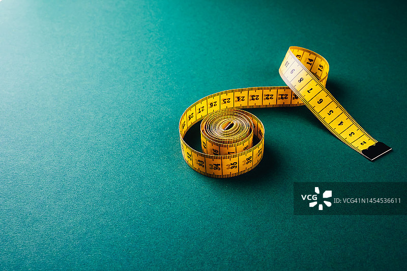 深绿色板上的黄色裁缝卷尺图片素材