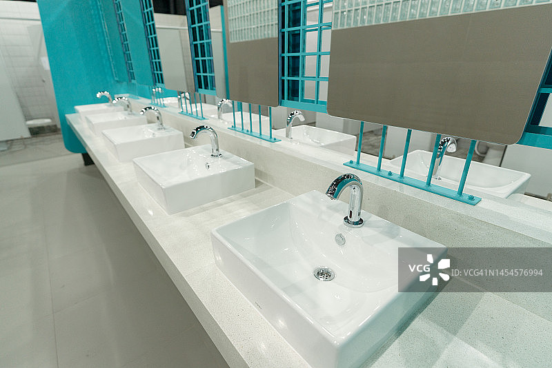 具有水槽龙头、大镜子和现代设计的公共卫生间内部图片素材