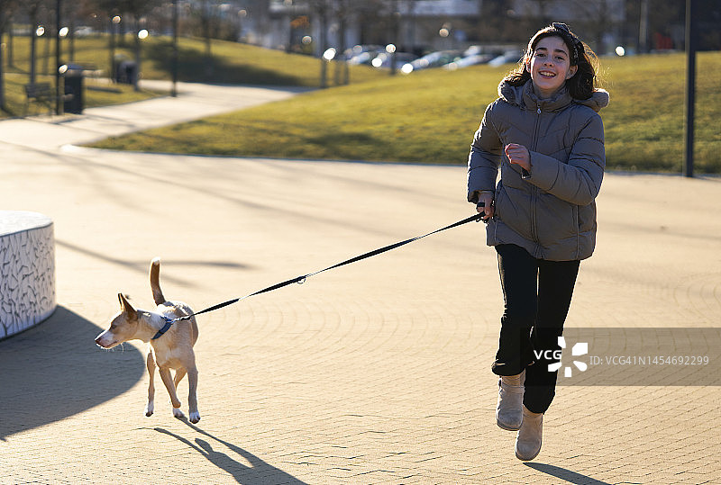 非常快乐的女孩在公园里和她的狗跑步和散步图片素材