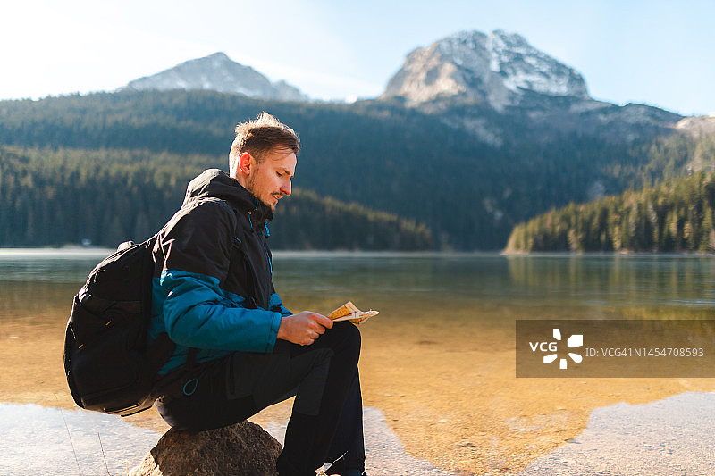 背包客在湖边看地图图片素材