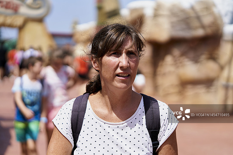 穿着带黑点的白色衬衫，背着包走在公园里的年轻女人图片素材