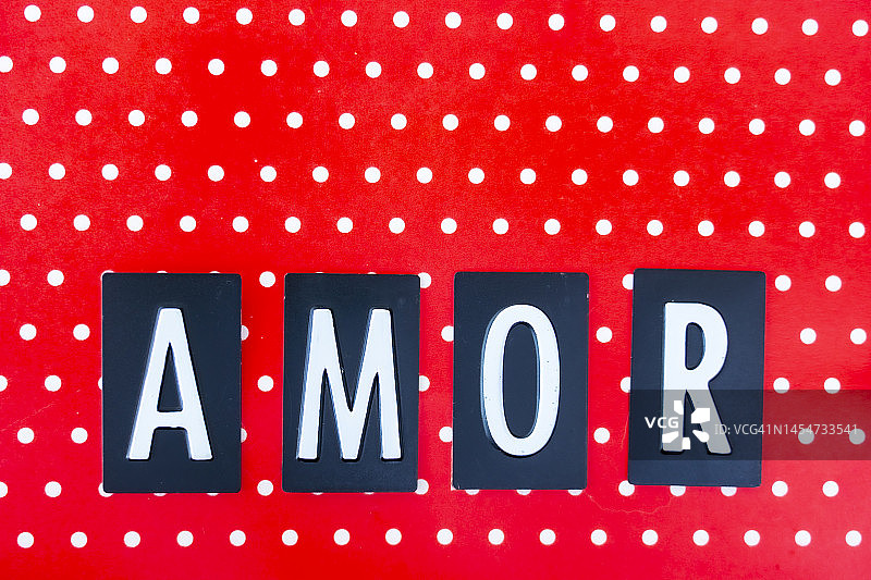 红色波点纸上的西班牙语“AMOR”（爱）图片素材