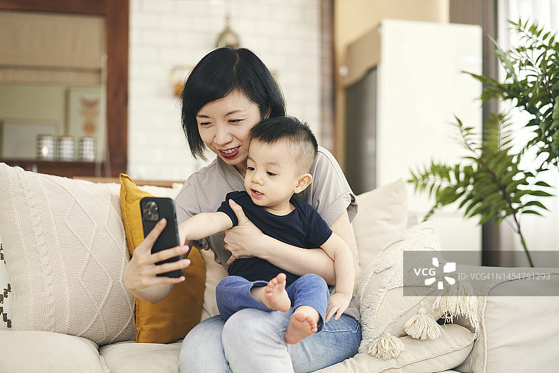 中国母亲和幼儿儿子愉快地使用智能手机进行视频通话图片素材