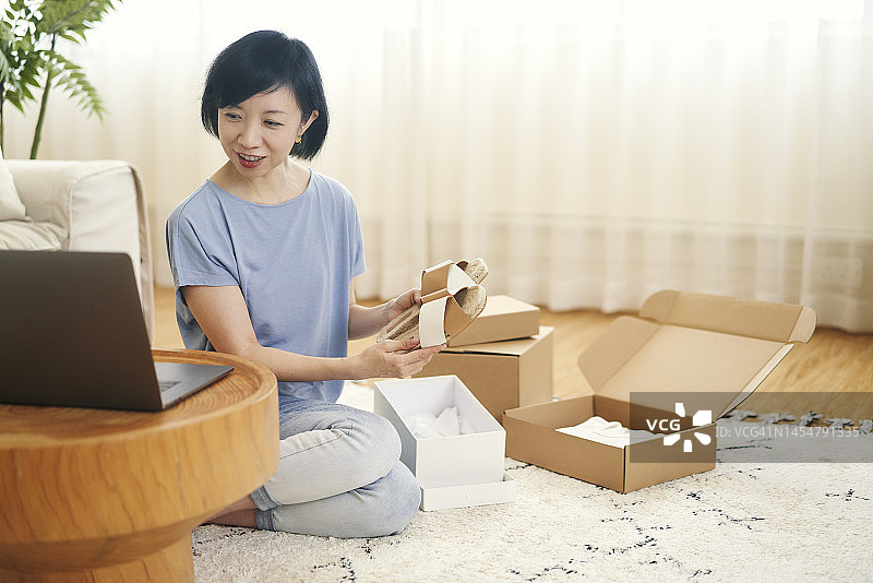 在香港的中国女人打开包裹检查网购凉鞋图片素材