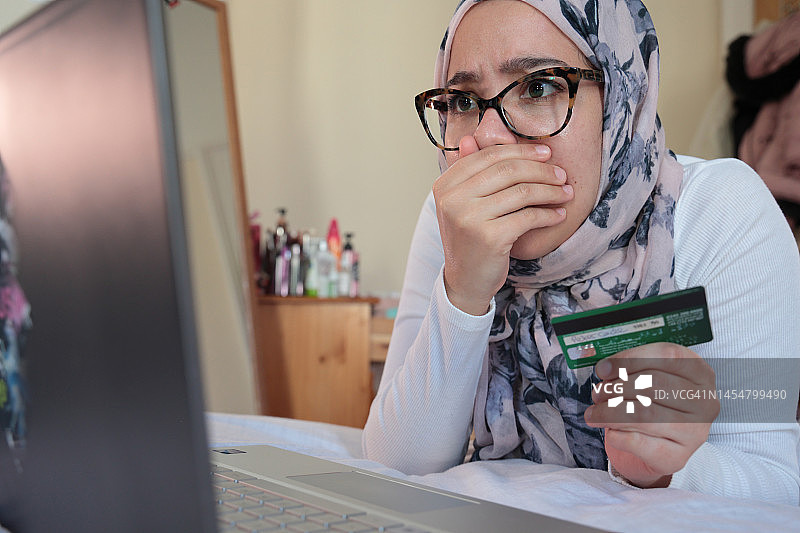 女人看着笔记本电脑屏幕，面露担忧图片素材