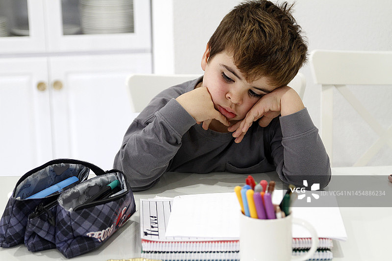 无聊的男孩在家做作业图片素材