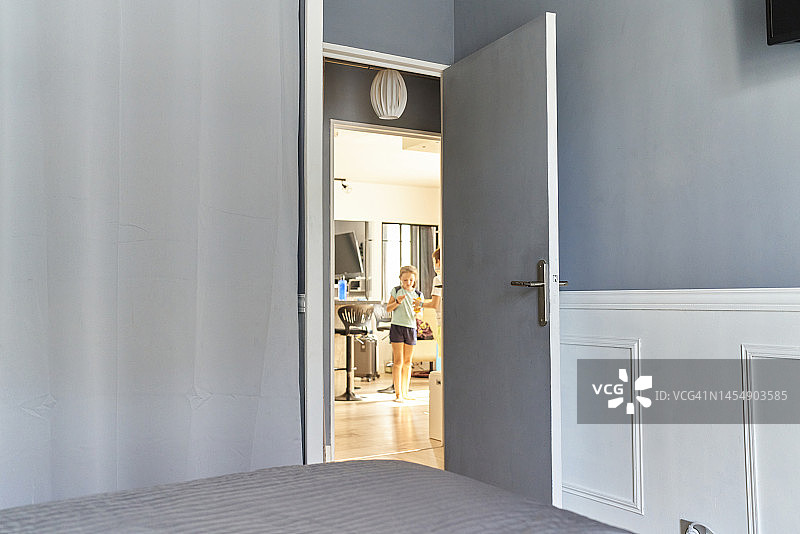 公寓里敞开的卧室门，背景是女孩们在客厅里聊天玩耍图片素材