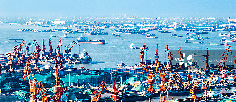 中国江苏省江阴市长江港口，巨大的起重机和航行的货船图片素材