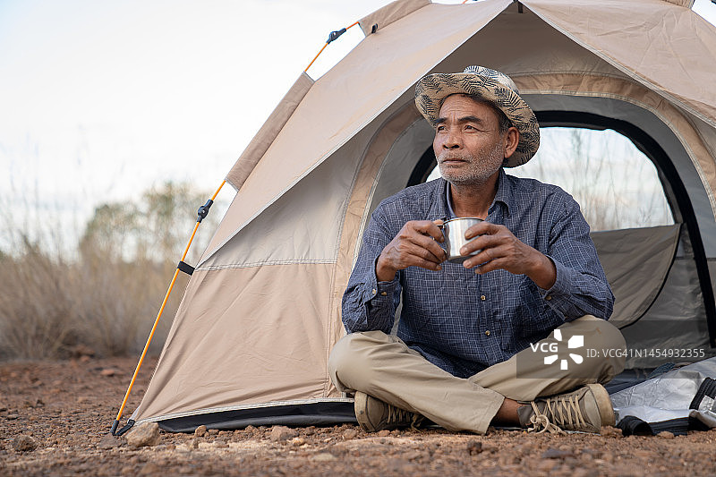 在露营帐篷里用锡杯喝东西的男人图片素材