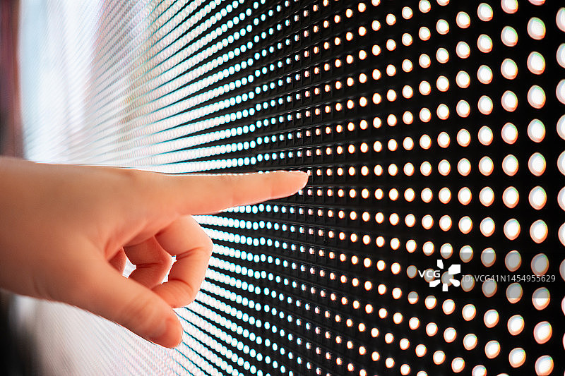 黑暗中，女性的手触摸发光数字显示屏的特写图片素材