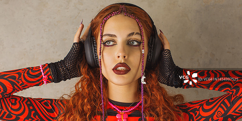 戴着耳机听音乐的红发女孩，精致妆容图片素材