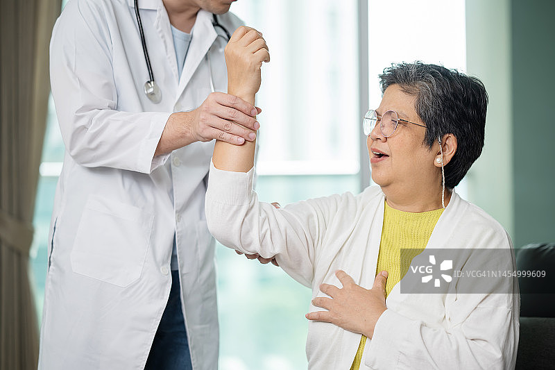 提高老年退休人员的灵活性和活动范围。男性理疗师在医疗诊所办公室检查亚洲老年患者的手臂图片素材