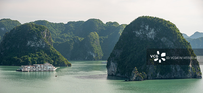 下龙湾日落时分的航拍镜头，乘坐游船穿梭于越南下龙湾，欣赏石灰岩悬崖和山脉的日落美景，感受宁静、自由的旅行和旅游概念（联合国教科文组织世界遗产地）图片素材