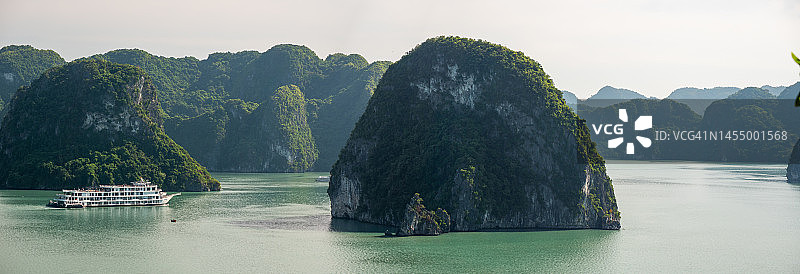 下龙湾日落时分的航拍镜头，乘坐游船穿梭于越南下龙湾，欣赏石灰岩悬崖和山脉的日落美景，感受宁静、自由的旅行和旅游概念（联合国教科文组织世界遗产地）图片素材
