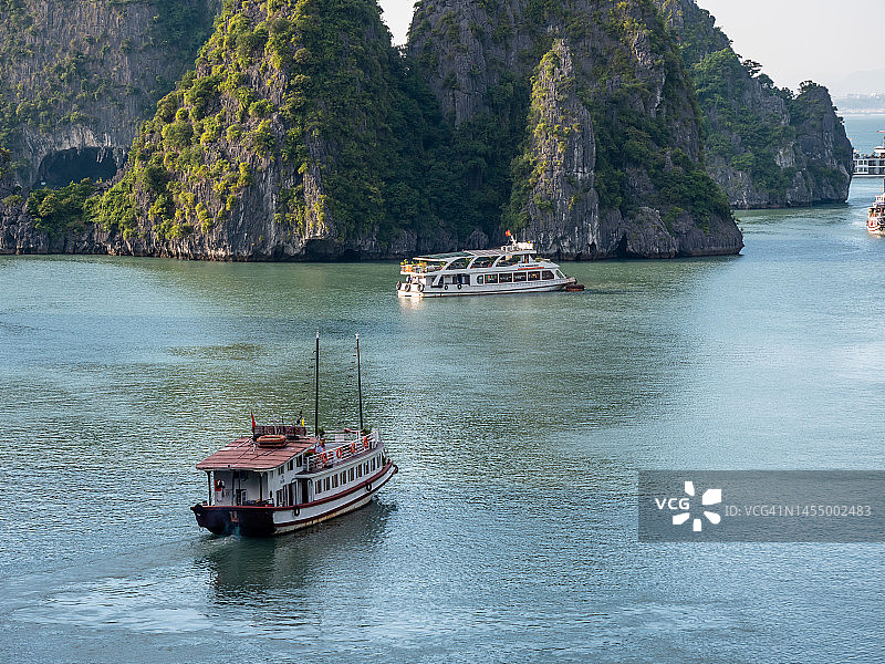 下龙湾日落时分的航拍镜头，乘坐游船穿梭于越南下龙湾，欣赏石灰岩悬崖和山脉的日落美景，感受宁静、自由的旅行和旅游概念（联合国教科文组织世界遗产地）图片素材
