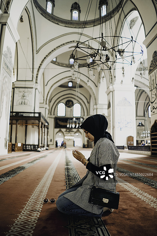 女子在清真寺跪着祈祷的侧视图图片素材
