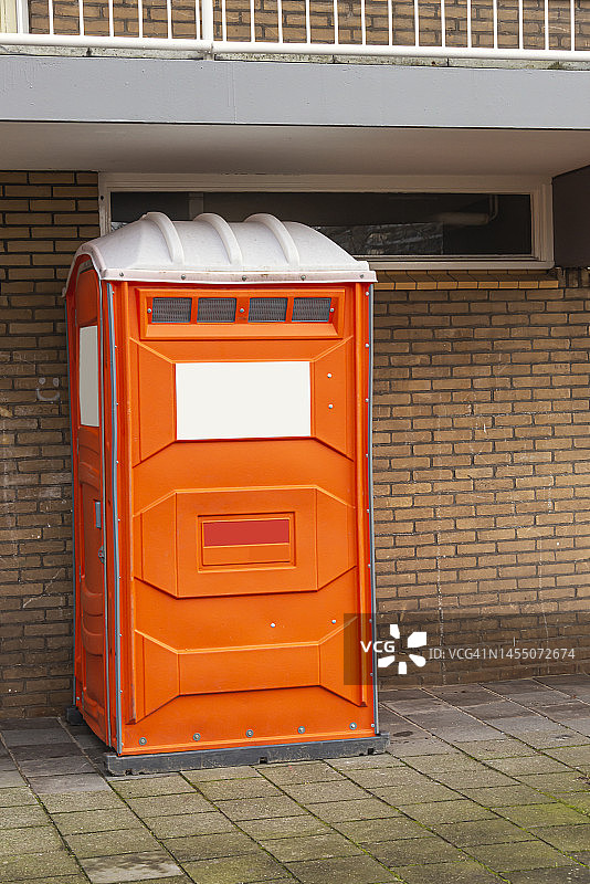 公寓楼附近的橙色移动厕所图片素材