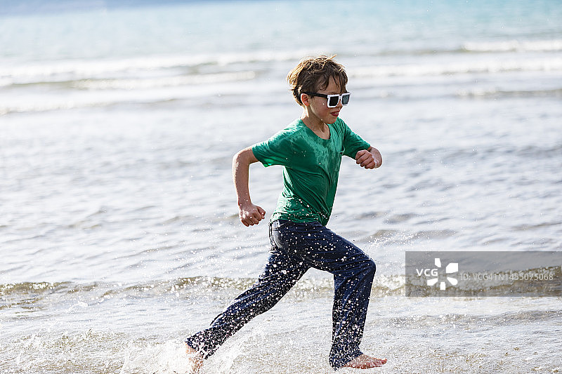 男孩在海滩上玩水图片素材