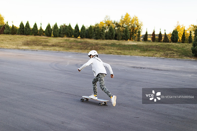 学龄男孩在公园里玩滑板图片素材