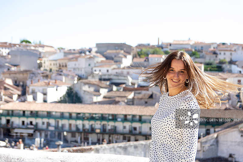 在白色房屋小镇里微笑的漂亮金发女孩图片素材