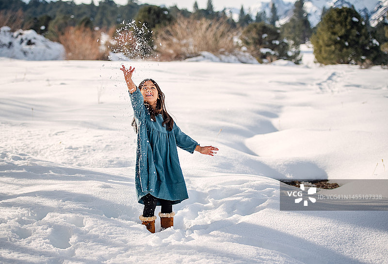 微笑的女孩向空中抛雪图片素材