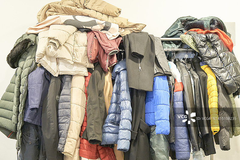 金属衣柜中悬挂和堆叠的彩色绗缝夹克图片素材