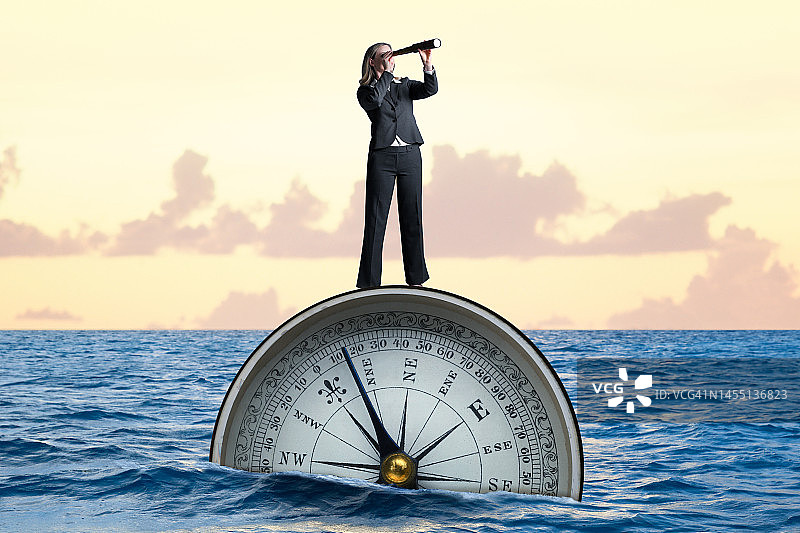 女人站在指南针上，通过望远镜观察图片素材