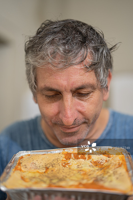 男子闻自制烤宽面条图片素材