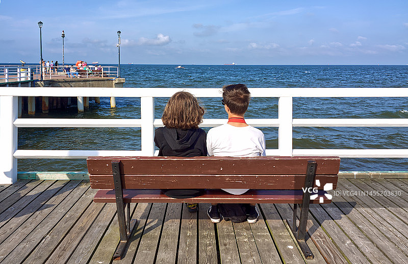 女孩和男孩坐在长椅上的背影图片素材